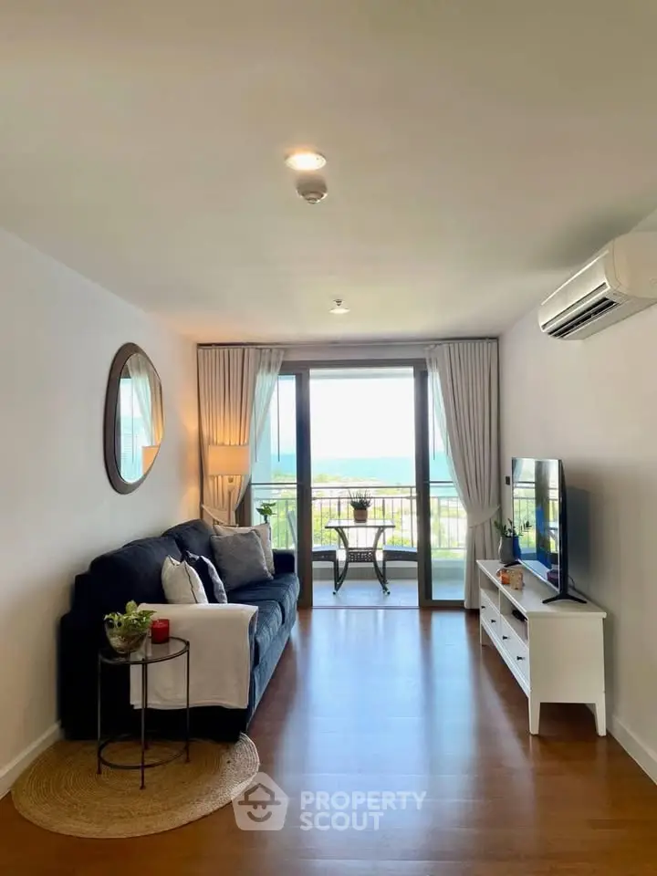 Modern living room with ocean view, featuring cozy sofa and sleek TV setup.