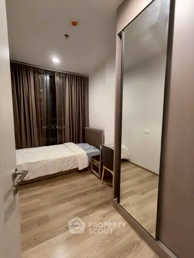 Modern bedroom with sleek design, large mirror, and floor-to-ceiling window for natural light.