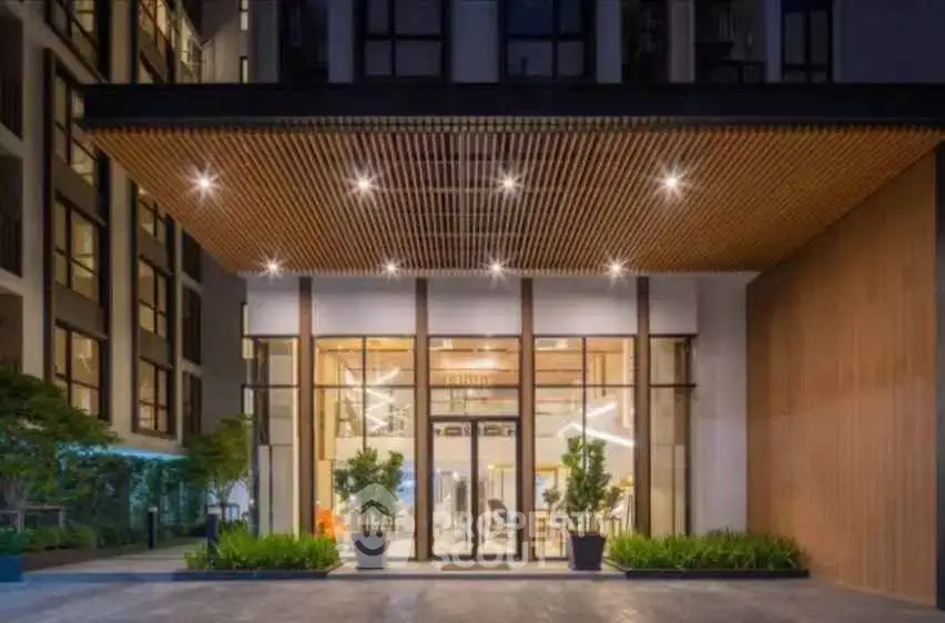 Modern building entrance with stylish lighting and greenery, showcasing contemporary architecture.