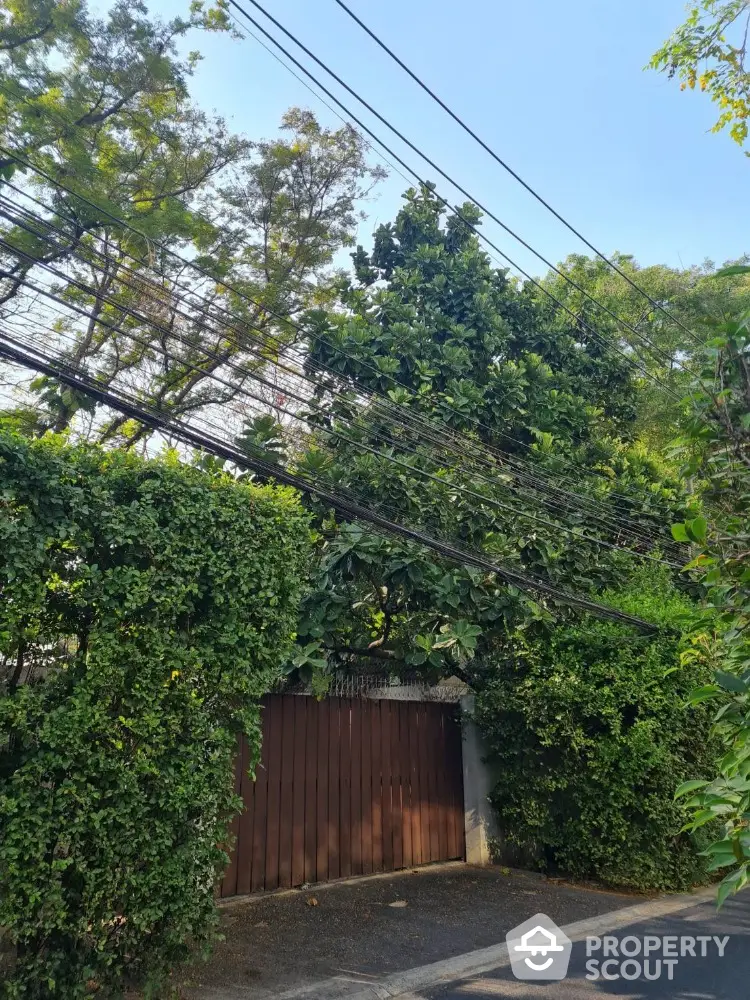 Charming residential entrance with lush greenery and wooden gate