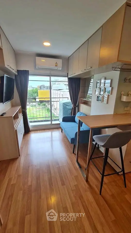 Modern living room with balcony view, stylish furniture, and ample natural light.