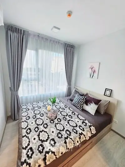 Cozy bedroom with stylish decor and large window offering natural light.