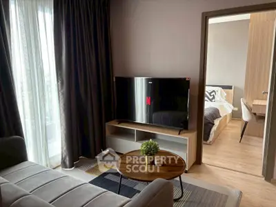 Modern living room with cozy sofa and TV, leading to a stylish bedroom.