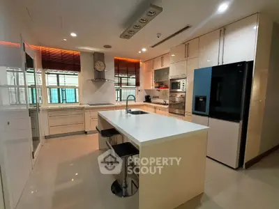 Modern kitchen with sleek white cabinetry, island seating, and stainless steel appliances.
