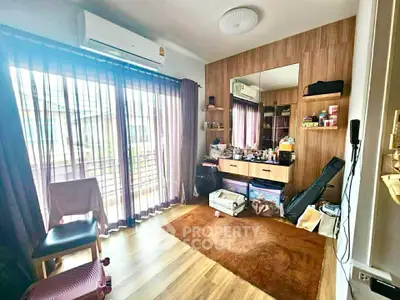 Spacious bedroom with large window and modern decor, featuring wooden flooring and ample natural light.