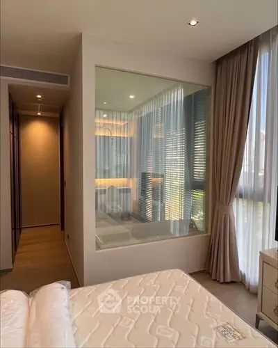 Modern bedroom with large window and stylish decor, featuring a unique glass partition.