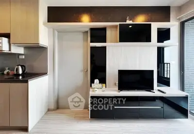 Modern living room with sleek TV unit and adjacent kitchen area, showcasing contemporary design and functionality.