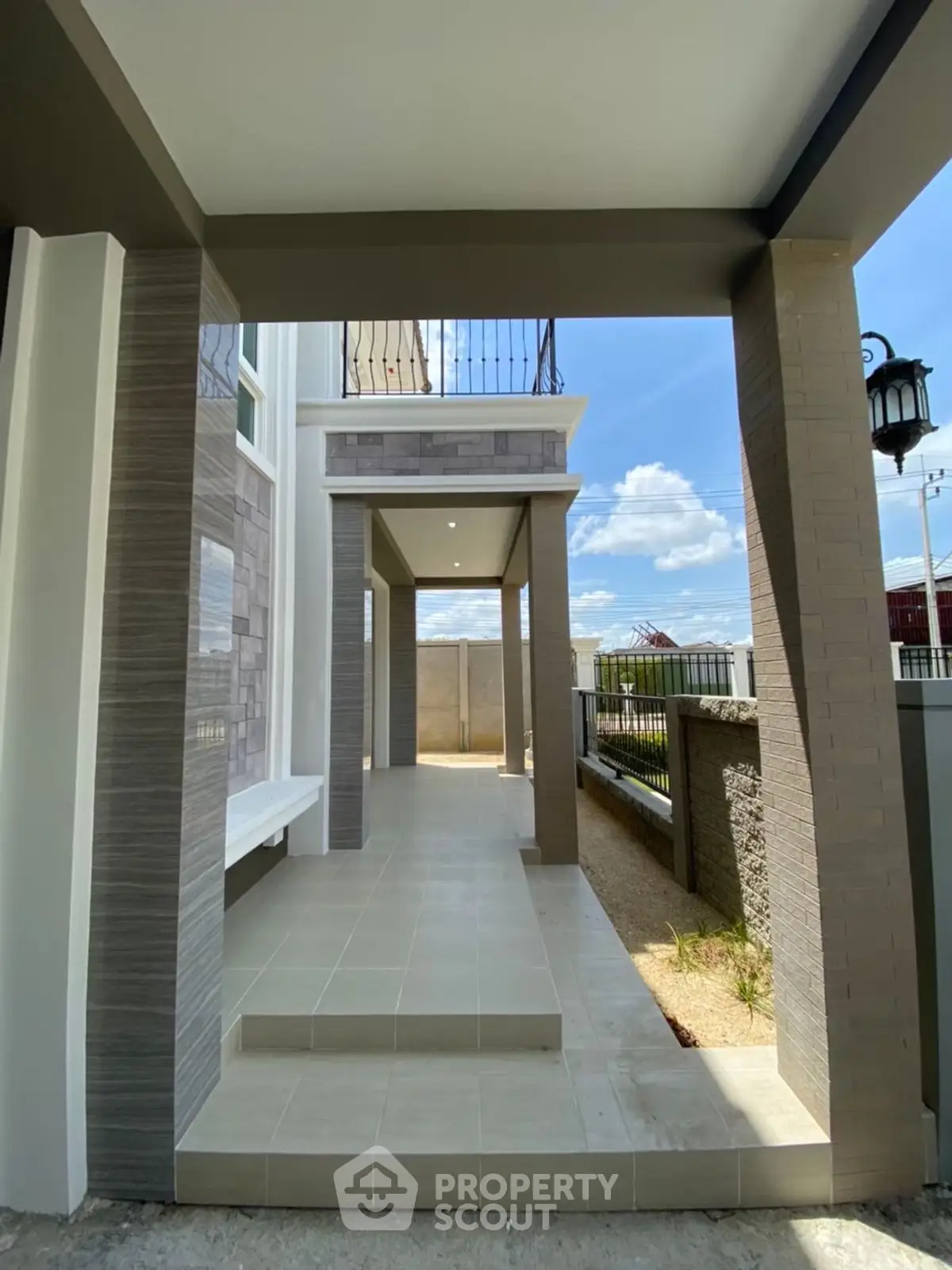 Modern exterior entrance with elegant columns and tiled flooring, showcasing a stylish and inviting home facade.