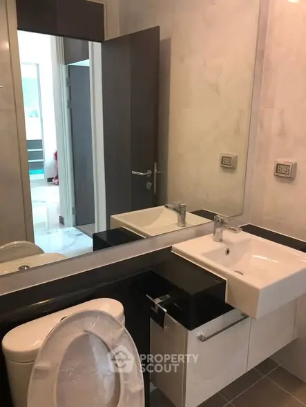 Modern bathroom with sleek fixtures and large mirror in a contemporary home.