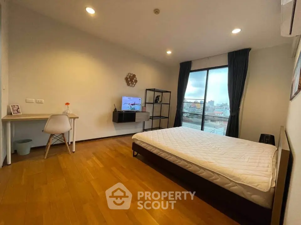 Spacious bedroom with modern decor and city view, featuring a cozy bed and stylish desk area.