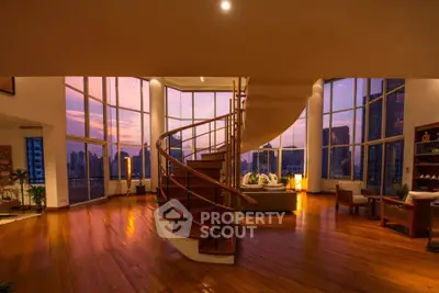 Luxurious penthouse living room with spiral staircase and panoramic city views at sunset.