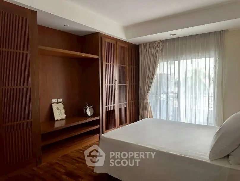 Spacious bedroom with elegant wooden wardrobe and large window for natural light