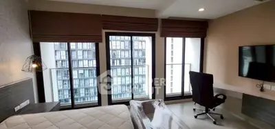 Modern bedroom with large windows and city view, featuring a desk and chair for a perfect work-from-home setup.
