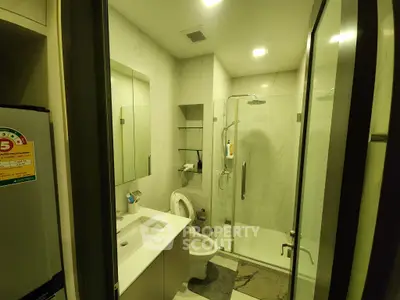 Modern bathroom with glass shower and sleek fixtures in luxury apartment.