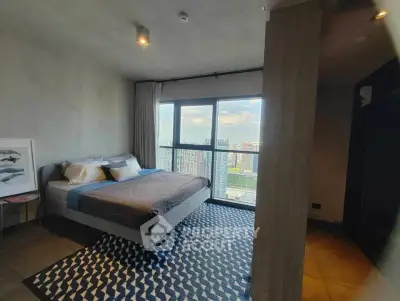 Spacious bedroom with large window offering stunning city views in modern apartment.