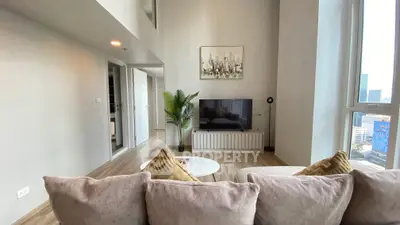 Modern living room with stylish decor and city view, featuring a cozy sofa and large TV.