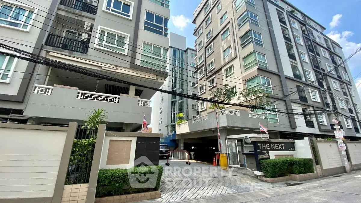 Modern urban condominium building with secure entrance and lush greenery.