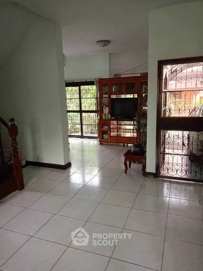 Spacious living room with tiled floor and large windows for natural light.