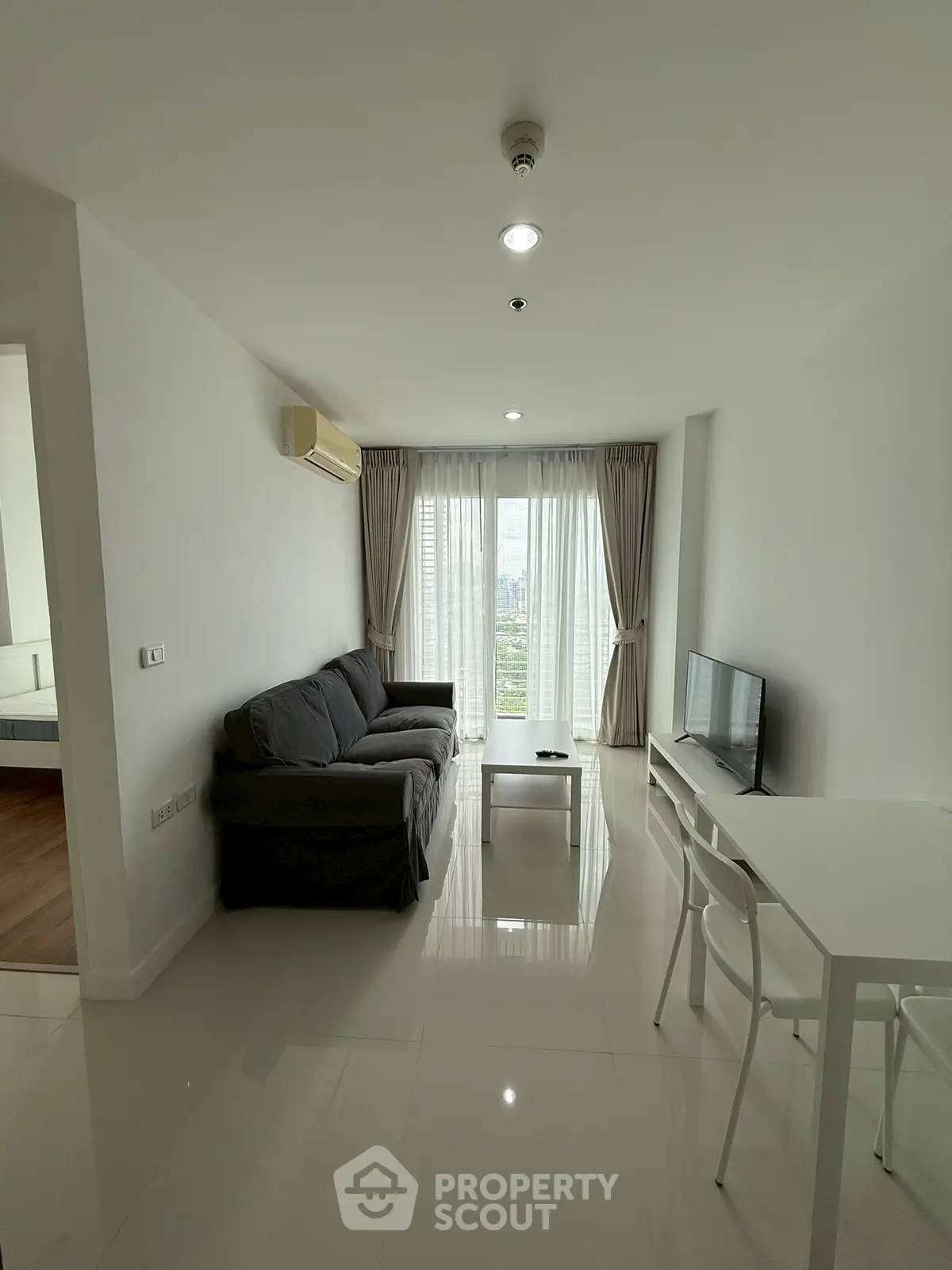 Modern living room with sleek furniture and large windows offering a stunning city view.