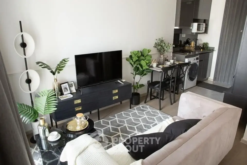 Modern living room with stylish decor and compact kitchen featuring washing machine and dining area.