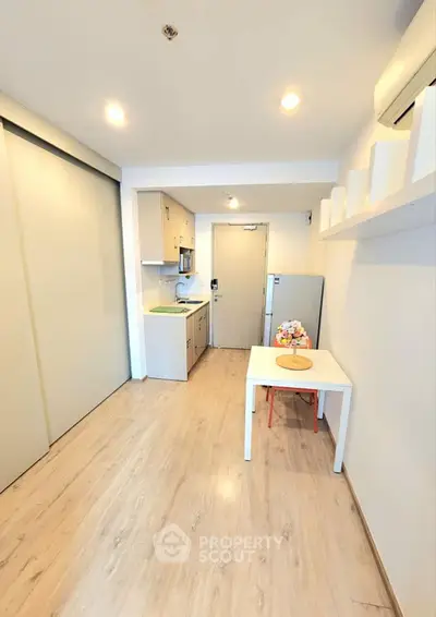 Modern compact studio apartment with sleek kitchen and cozy dining area.