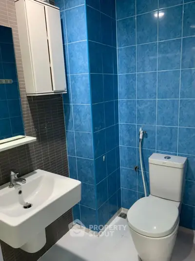 Modern bathroom with blue tiles and sleek fixtures in a contemporary apartment.