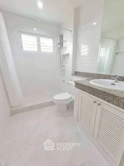 Bright and modern bathroom with sleek white tiles and a spacious shower area.