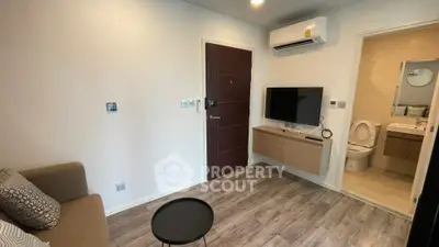 Modern living room with sleek design and attached bathroom, featuring air conditioning and wall-mounted TV.