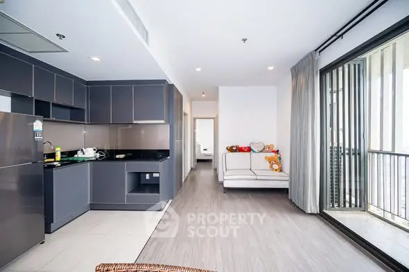 Modern open-plan kitchen and living area with balcony access in a stylish apartment.