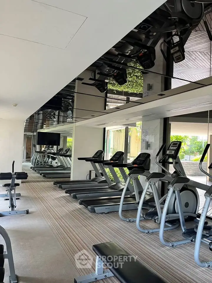 Modern gym with state-of-the-art equipment and large mirrors in a luxury residential building.
