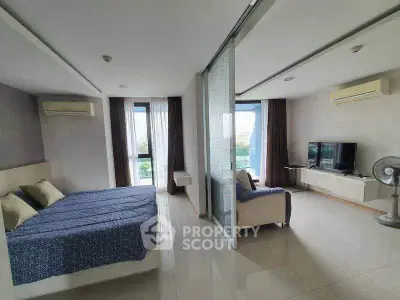 Spacious modern studio with sliding glass partition, featuring a cozy bed and stylish living area.