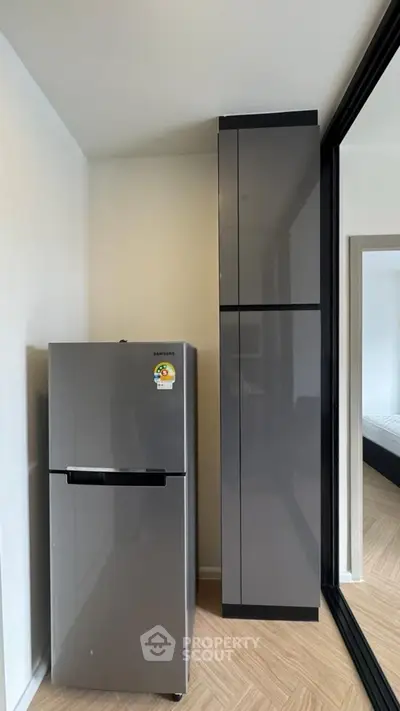 Modern kitchen corner with sleek fridge and storage cabinets in a stylish apartment.
