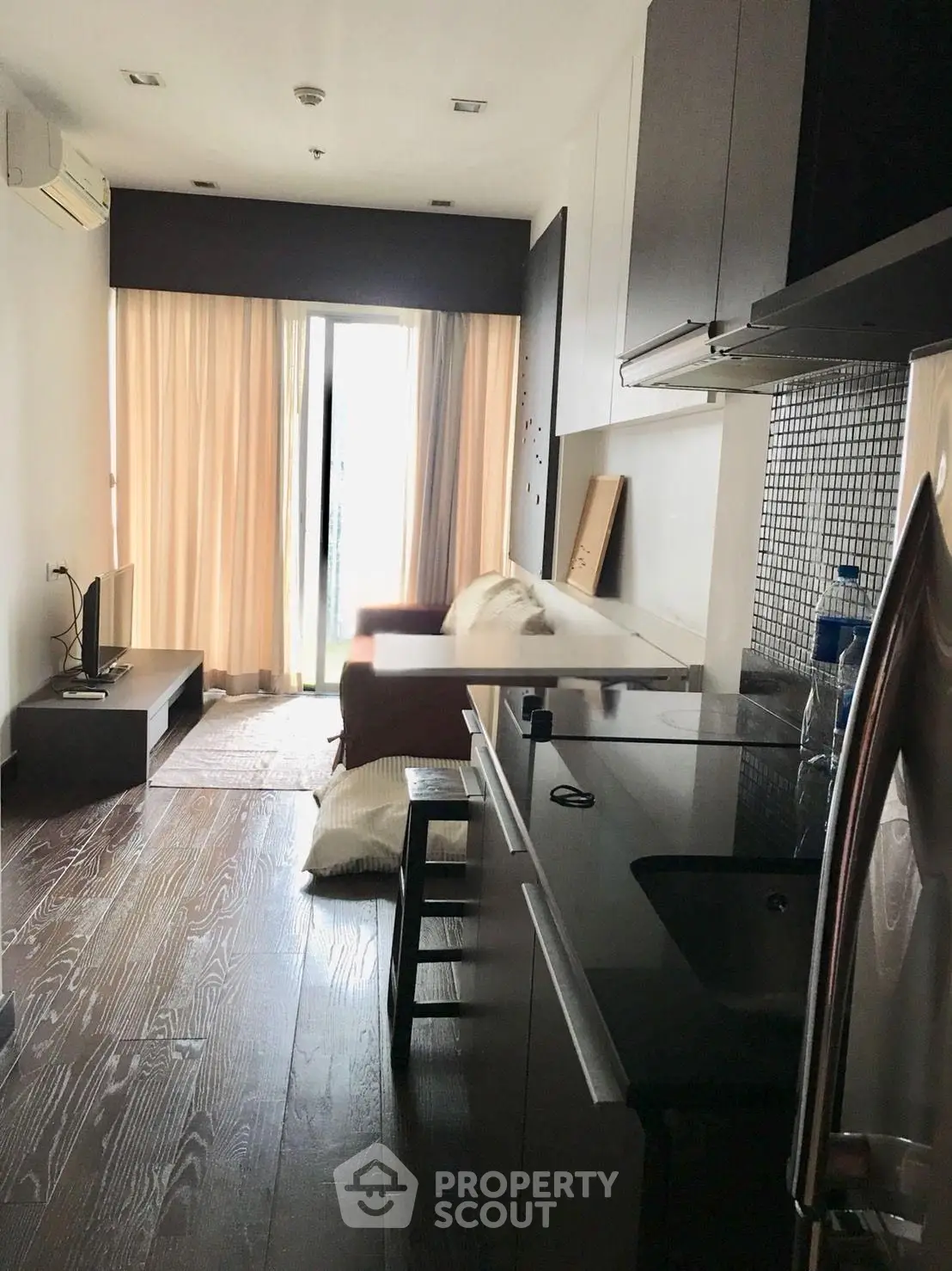Modern apartment with open kitchen and cozy living area, featuring sleek design and natural light.