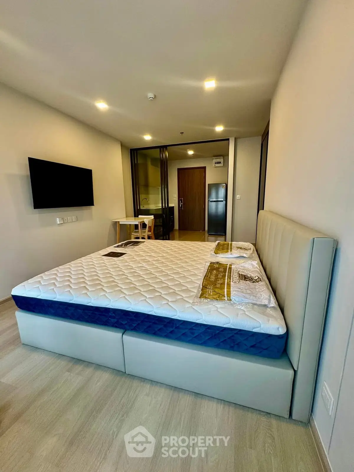 Modern bedroom with stylish bed and wall-mounted TV in a contemporary apartment.