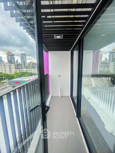 Modern balcony with city view, sleek glass railing, and adjacent bedroom access in urban apartment.