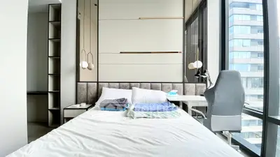 Modern bedroom with large windows and stylish furniture in a high-rise building.