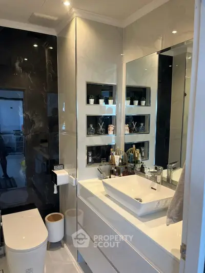 Modern bathroom with sleek design and elegant fixtures, featuring a large mirror and stylish sink.