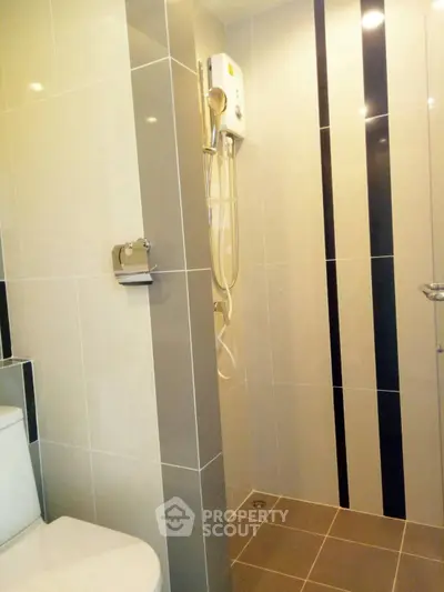 Modern bathroom with sleek tiles and shower unit in contemporary apartment.