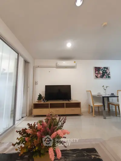 Modern living room with sleek furniture and elegant decor, featuring a TV and dining area.