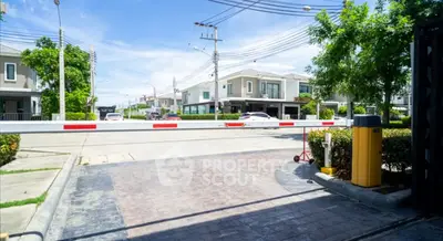 Gated community entrance with modern houses and lush greenery