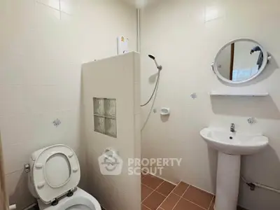 Compact bathroom with shower, toilet, and sink in a minimalist design.
