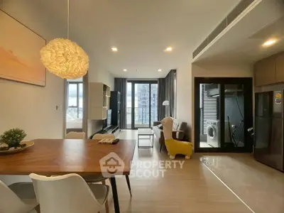 Modern open-plan living room with dining area and balcony view in a stylish apartment.