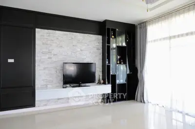 Modern living room with sleek TV setup and large windows for natural light.