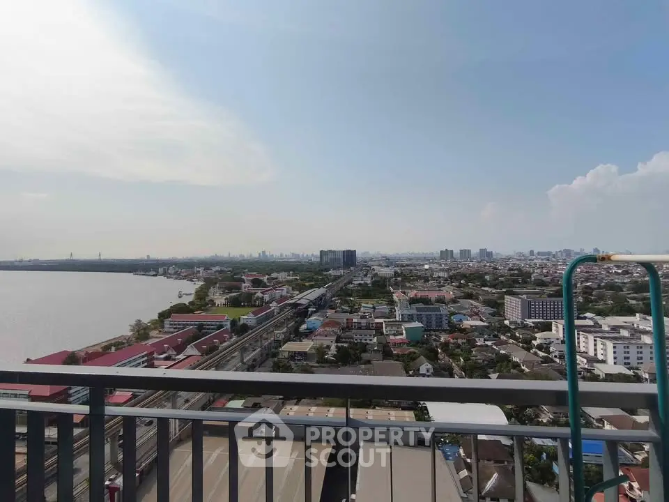 Stunning cityscape view from a high-rise balcony overlooking urban skyline and river.
