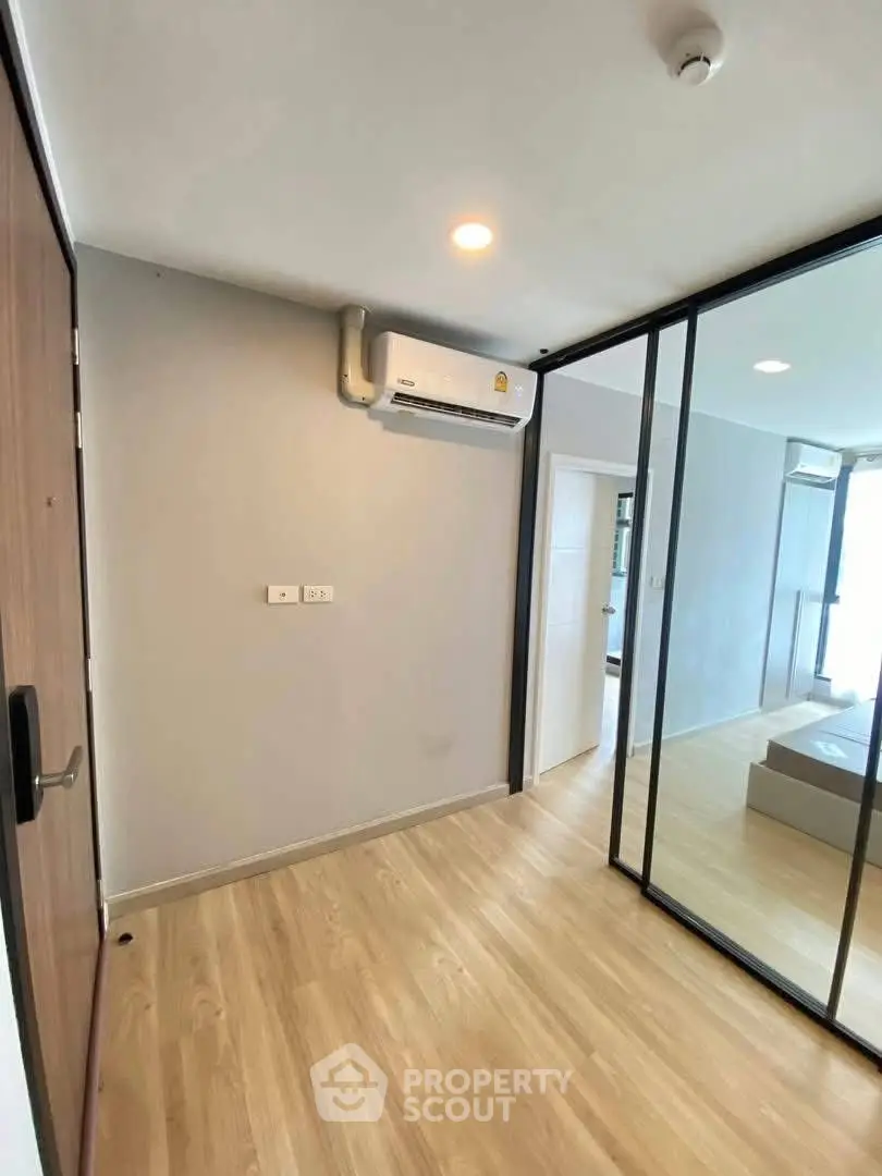 Modern apartment interior with wooden flooring and glass partition, featuring air conditioning.
