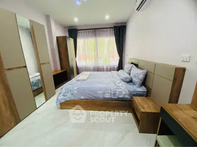 Spacious bedroom with modern furniture and large window offering natural light