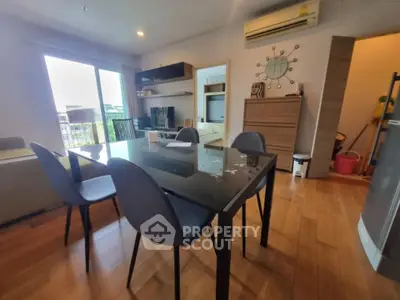 Modern dining area with sleek glass table and stylish chairs in a cozy apartment setting.