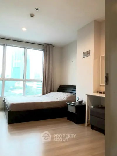 Modern bedroom with large windows and city view, featuring cozy bed and stylish decor.