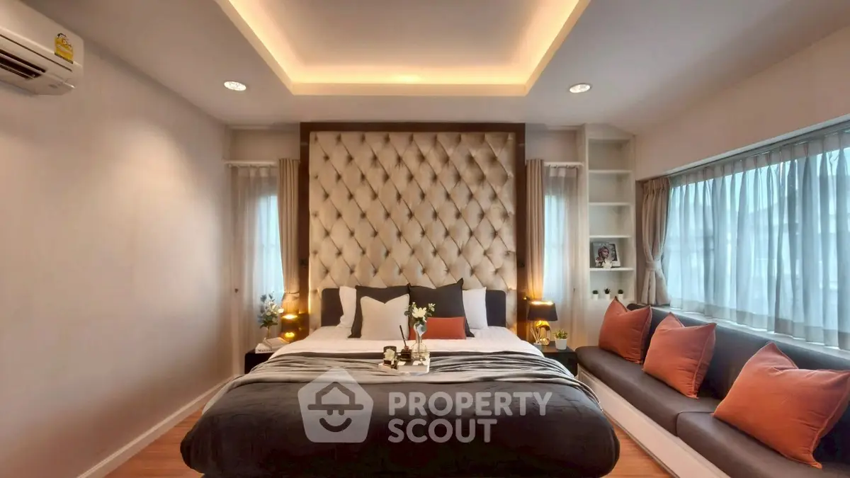 Luxurious bedroom with elegant tufted headboard and cozy seating area by the window.