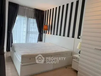 Modern bedroom with striped accent wall and large window with sheer curtains.